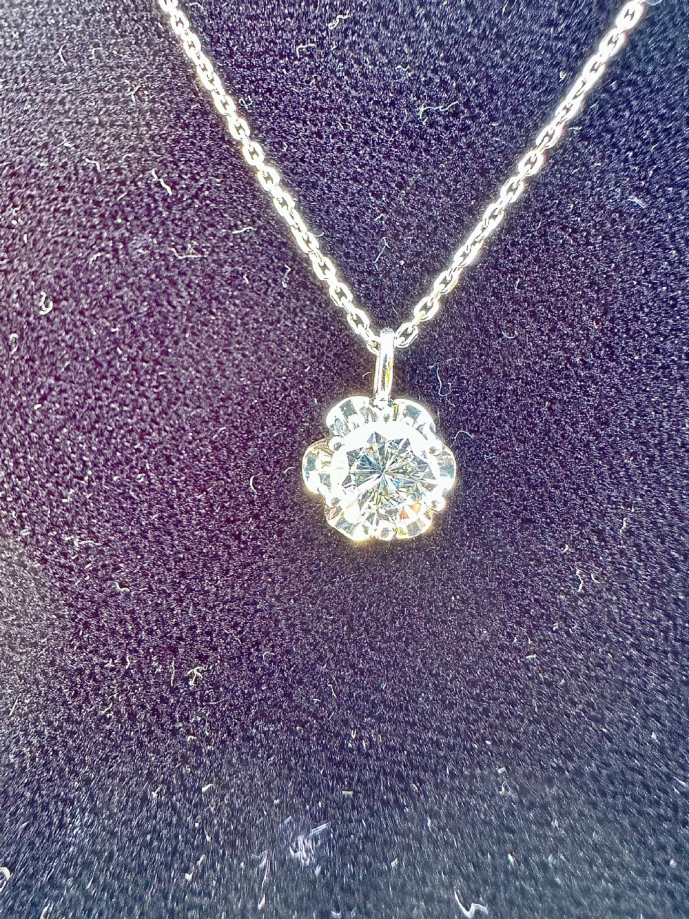 A single 0.60 carat diamond set inside a fluted white gold illusion pendant on a matching white gold chain.
