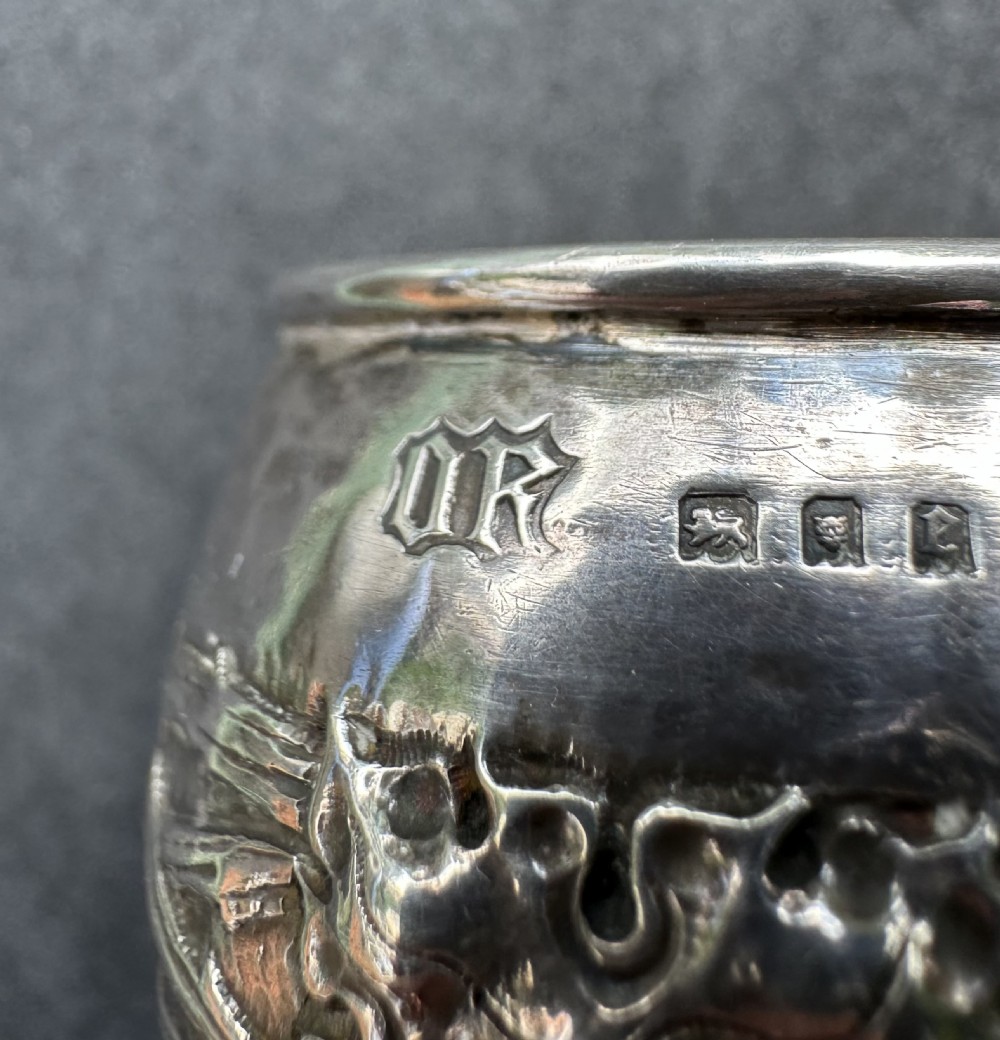 A hand-hammered sterling silver barrel-shaped napkin ring with an embossed relief band and rolled borders. View III
