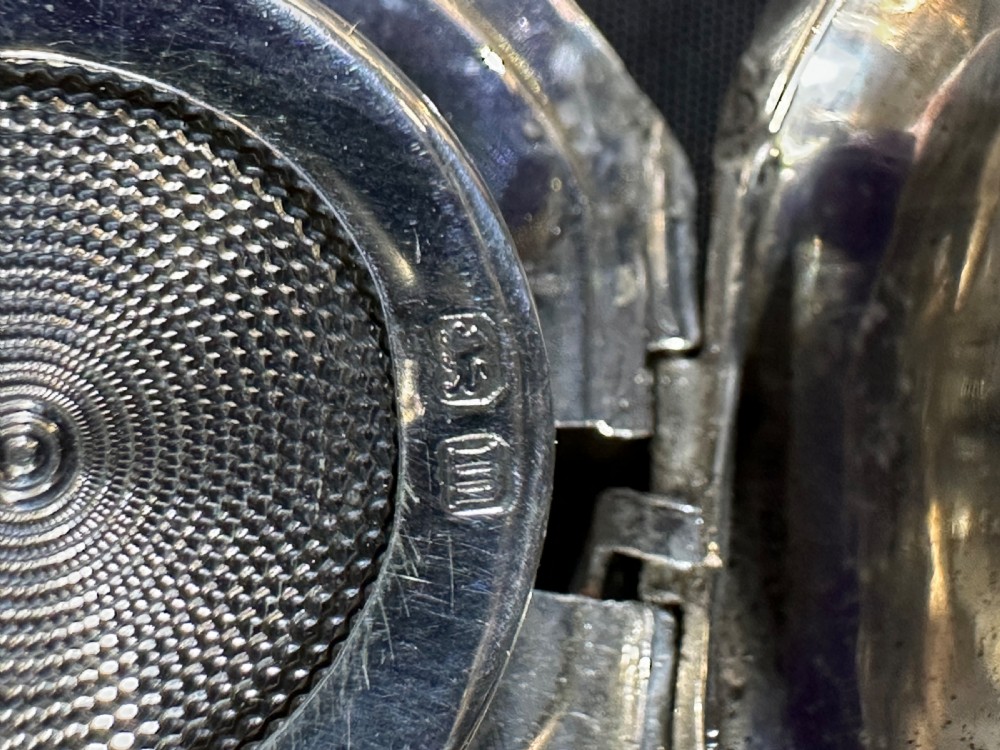 An open Edwardian sterling silver circular sovereign case showcasing an internal engine-turned spring-loaded coin platform and silver hallmarks. View II
