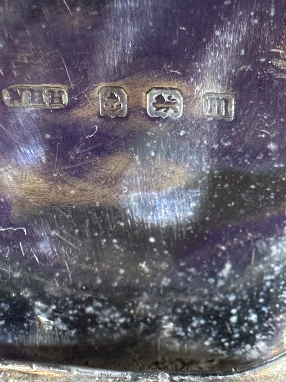 An open Edwardian sterling silver circular sovereign case showcasing an internal engine-turned spring-loaded coin platform and silver hallmarks. View III