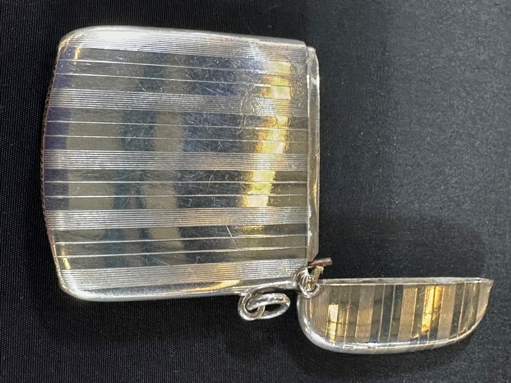 An engine-turned sterling silver vesta case featuring a central round enamelled plaque depicting three golfers on a golf course. View II