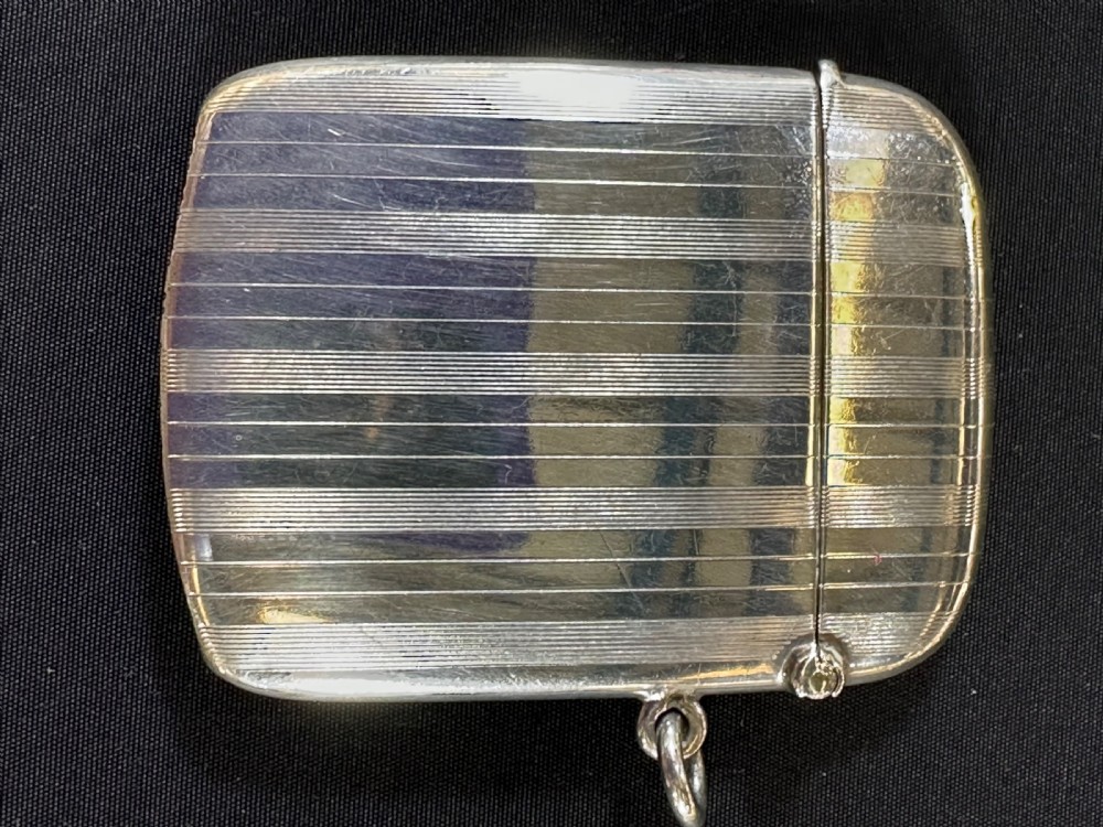 An engine-turned sterling silver vesta case featuring a central round enamelled plaque depicting three golfers on a golf course. View III