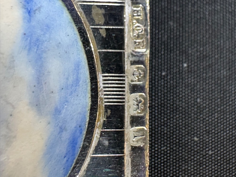 An engine-turned sterling silver vesta case featuring a central round enamelled plaque depicting three golfers on a golf course. View VII