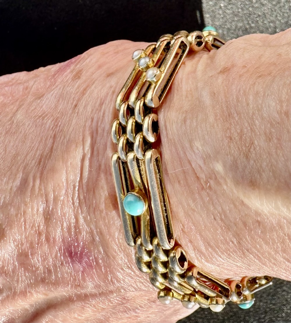 An antique 15ct yellow gold link bracelet featuring set turquoise cabochons and small seed pearls along structured openwork links.