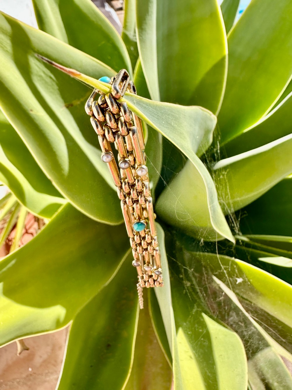 An antique 15ct yellow gold link bracelet featuring set turquoise cabochons and small seed pearls along structured openwork links. View III