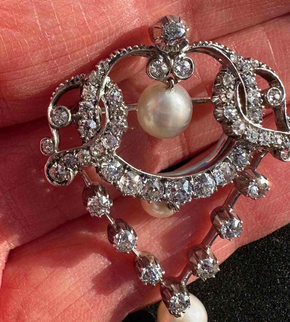A platinum openwork pendant brooch featuring diamond-set scrollwork and three suspended natural pearl drops. View III