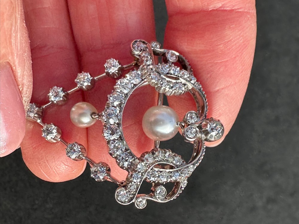 A platinum openwork pendant brooch featuring diamond-set scrollwork and three suspended natural pearl drops. View VII