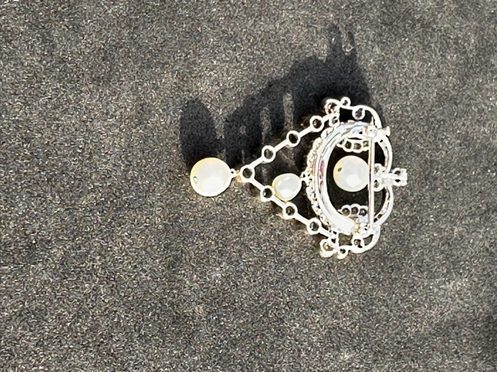 A platinum openwork pendant brooch featuring diamond-set scrollwork and three suspended natural pearl drops. View VIII