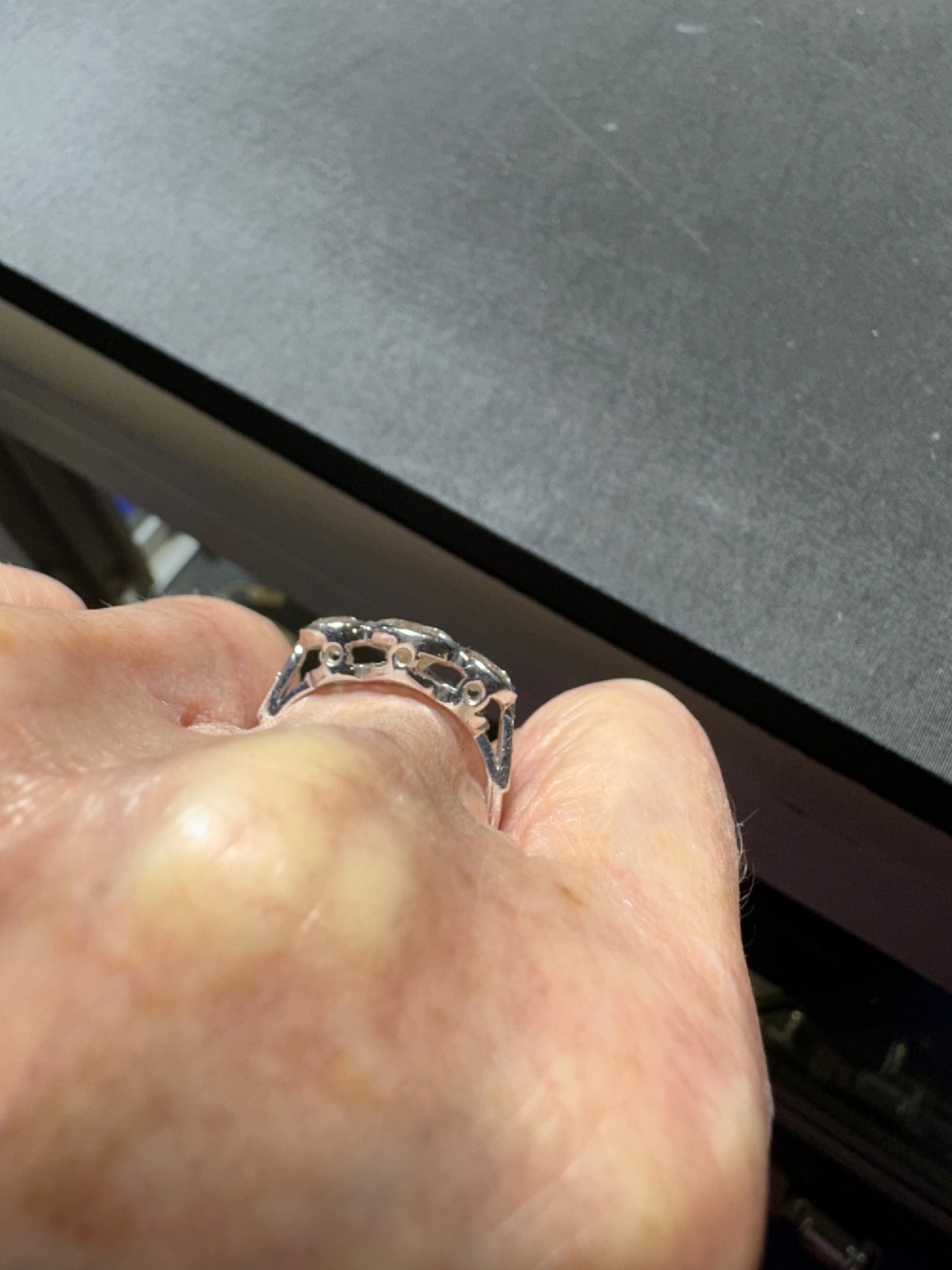 An 18ct white gold trinity ring featuring three round brilliant diamonds in rub-over bezel settings with millegrain edging. View III
