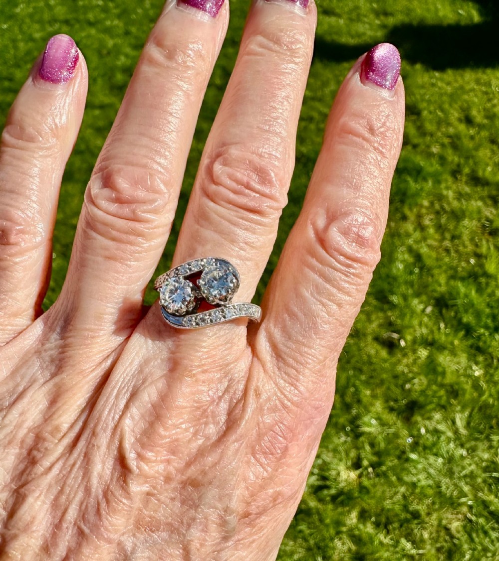 A vintage 14ct white gold double twist ring featuring two central round diamonds encircled by pave-set diamond accents with milgrain detailing. View III
