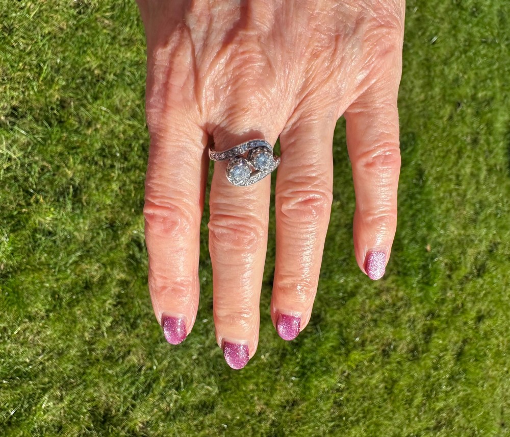 A vintage 14ct white gold double twist ring featuring two central round diamonds encircled by pave-set diamond accents with milgrain detailing. View IV