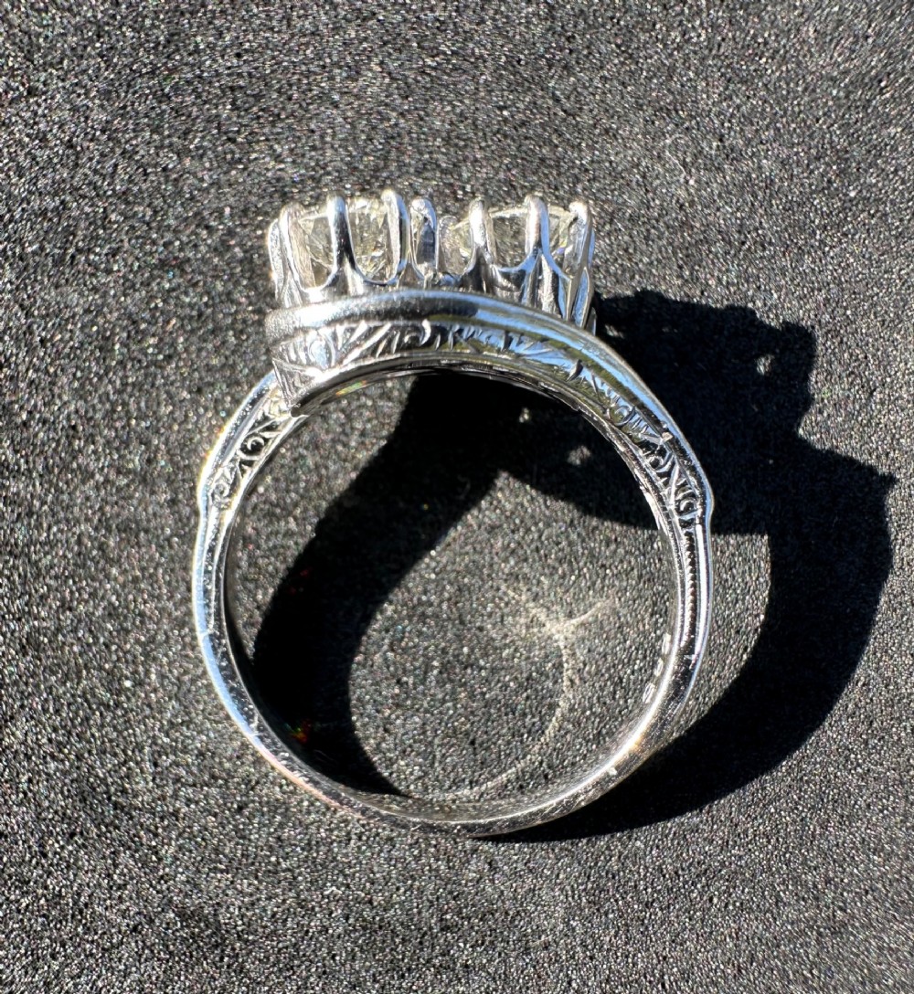 A vintage 14ct white gold double twist ring featuring two central round diamonds encircled by pave-set diamond accents with milgrain detailing. View V