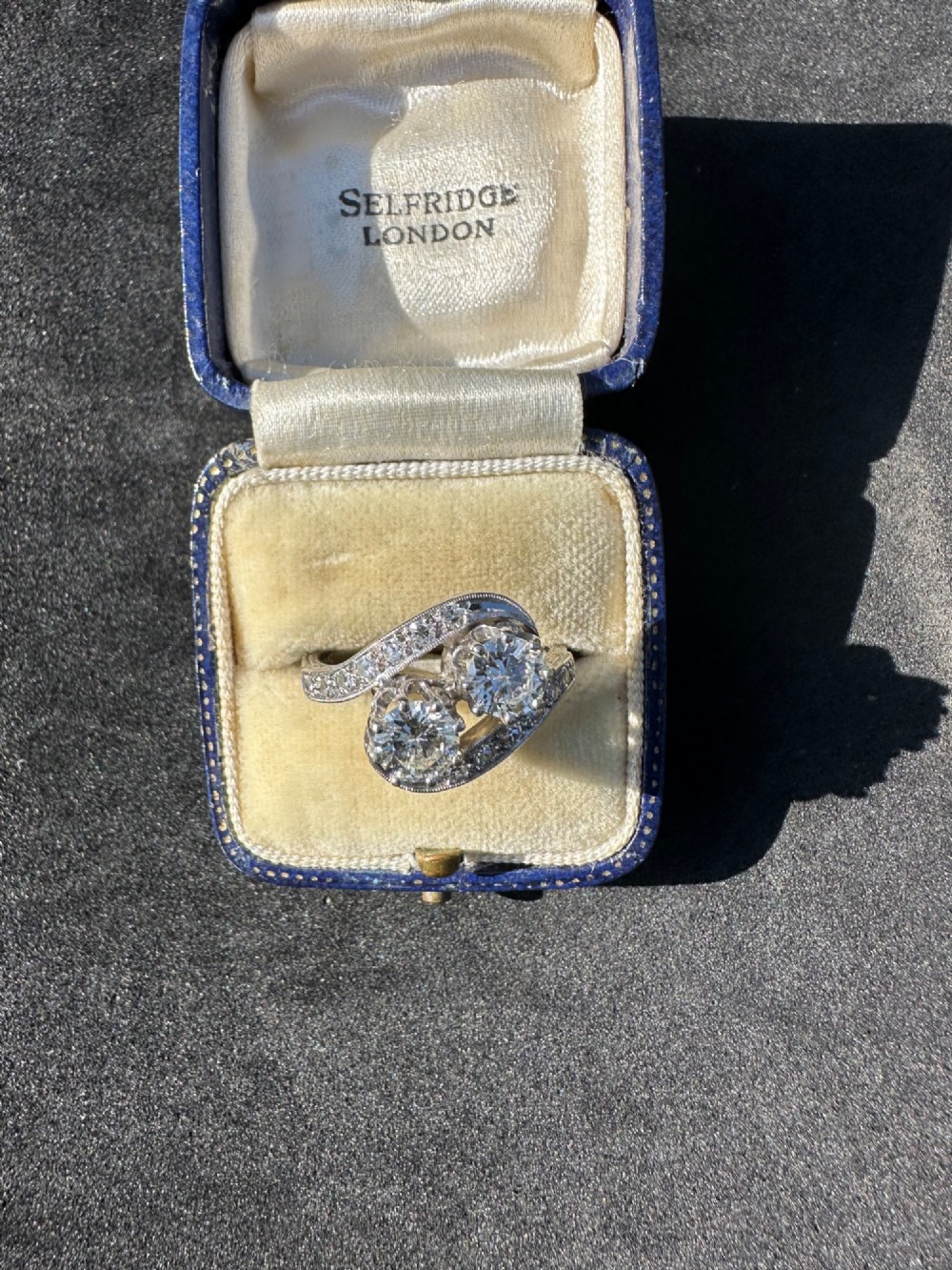 A vintage 14ct white gold double twist ring featuring two central round diamonds encircled by pave-set diamond accents with milgrain detailing. View VI