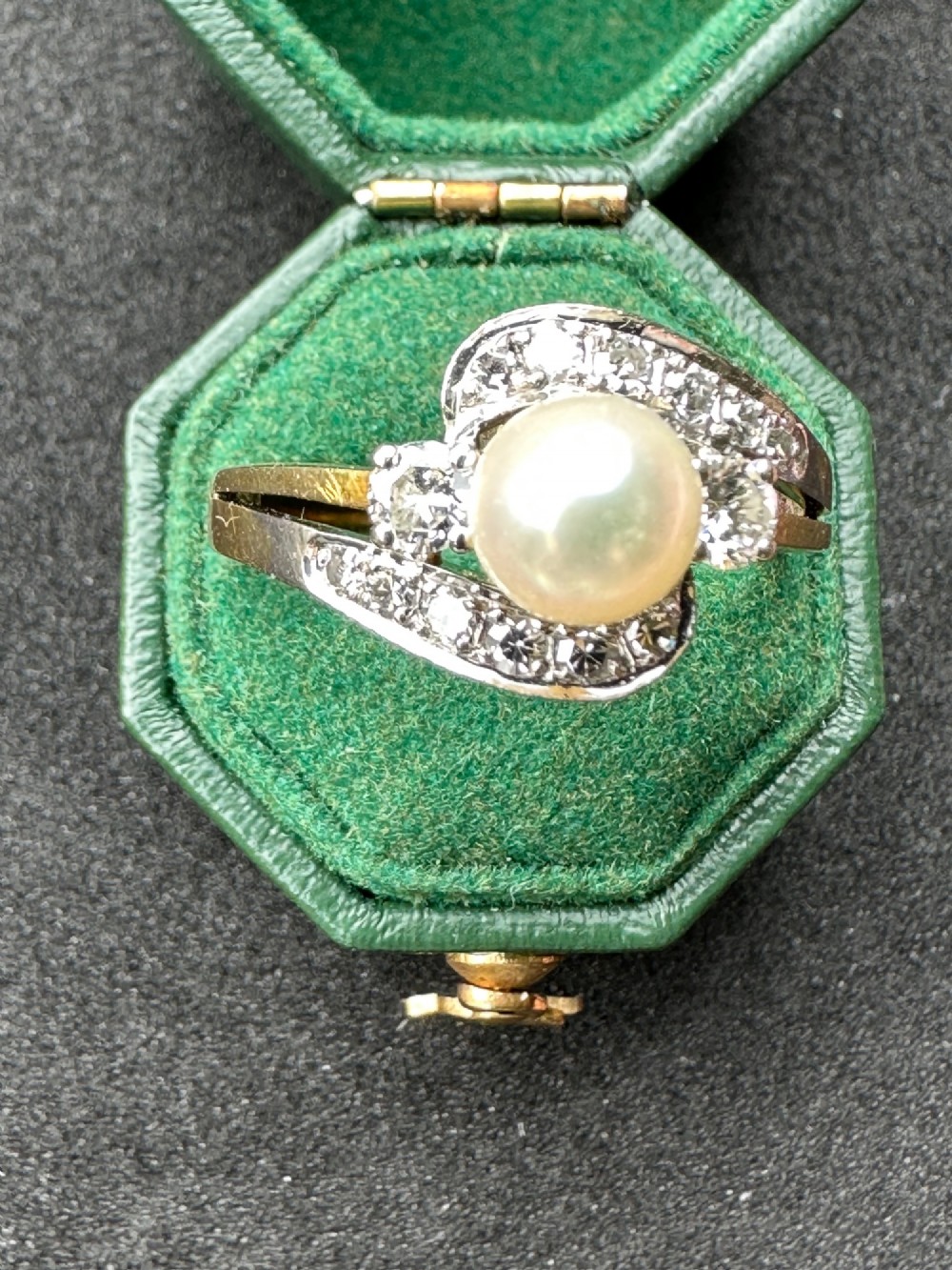 A 14ct gold crossover ring featuring a single central white pearl flanked by sweeping diamond-set bypass shoulders.