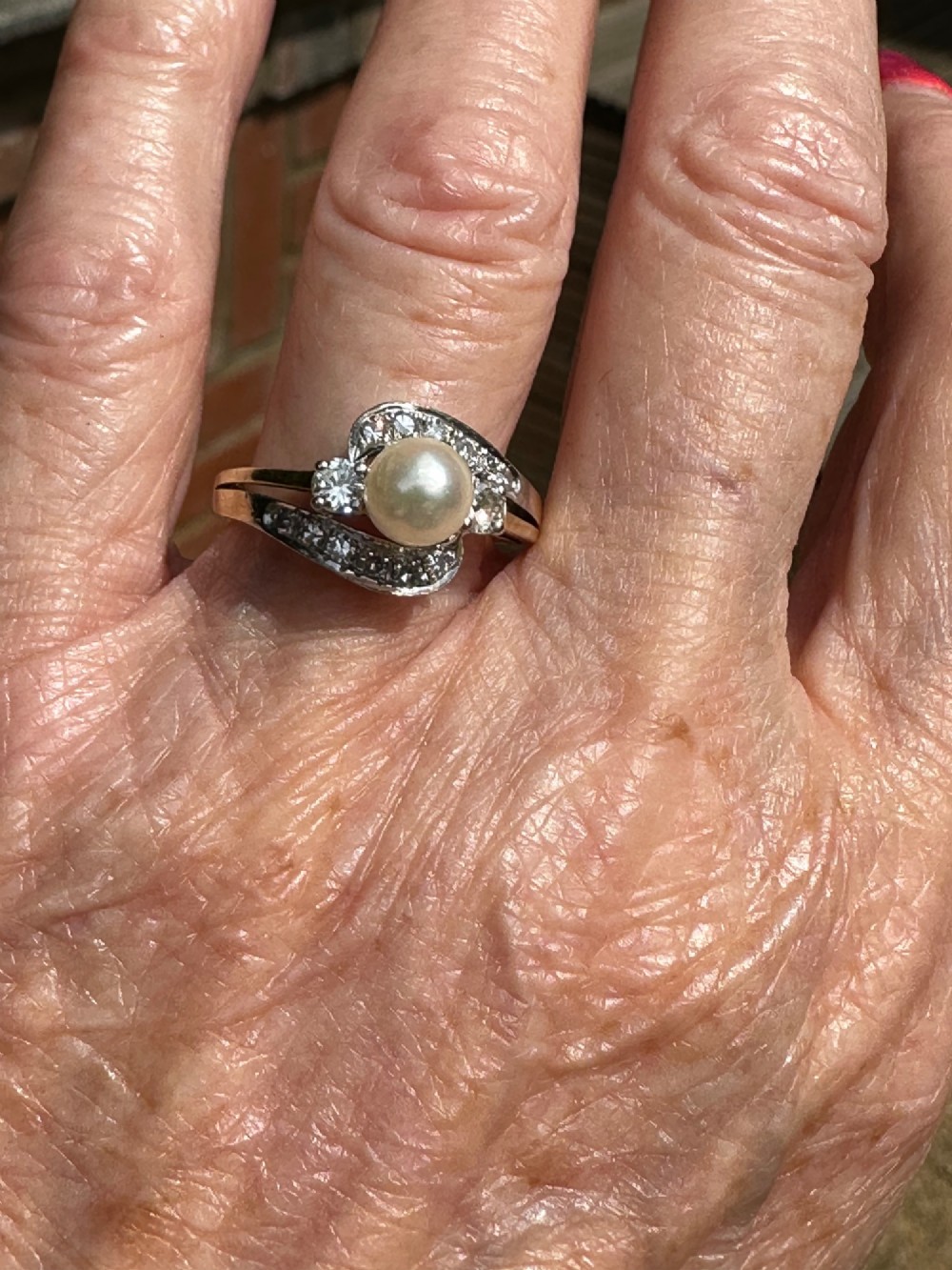 A 14ct gold crossover ring featuring a single central white pearl flanked by sweeping diamond-set bypass shoulders. View IV