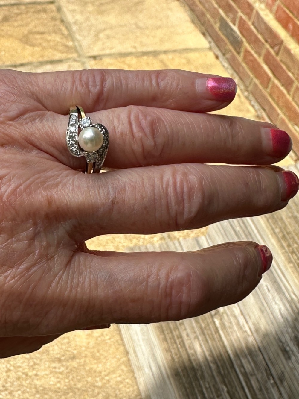 A 14ct gold crossover ring featuring a single central white pearl flanked by sweeping diamond-set bypass shoulders. View V