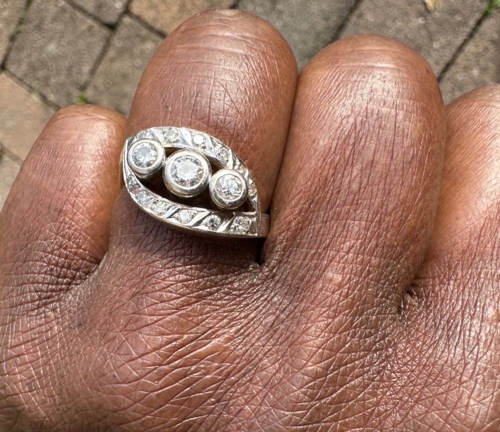 A 14ct white gold ring featuring a navette-shaped face set with three central diamonds and a curved outer frame of smaller accent diamonds.