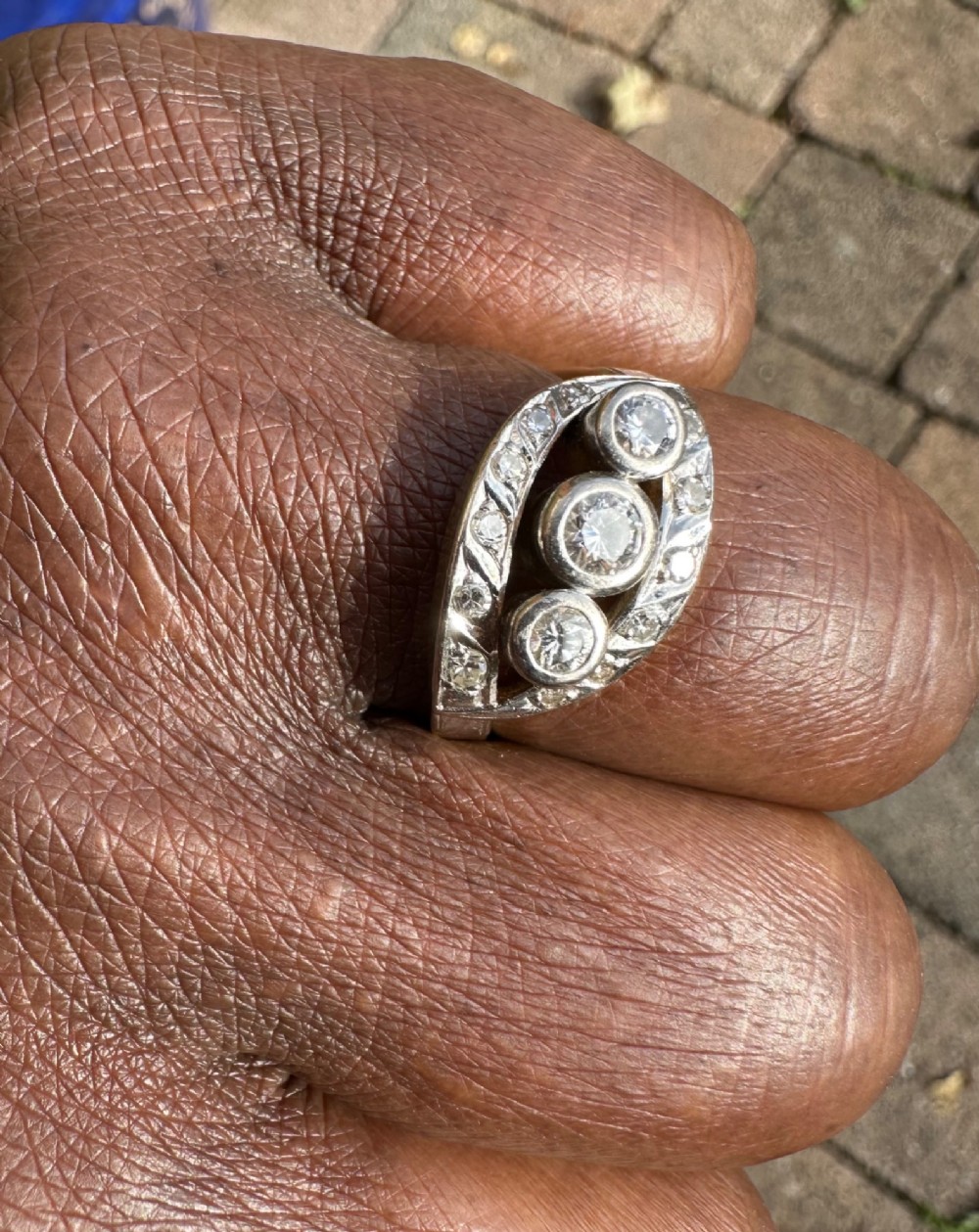 A 14ct white gold ring featuring a navette-shaped face set with three central diamonds and a curved outer frame of smaller accent diamonds. View II