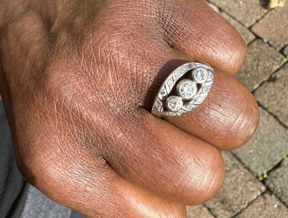 A 14ct white gold ring featuring a navette-shaped face set with three central diamonds and a curved outer frame of smaller accent diamonds. View III