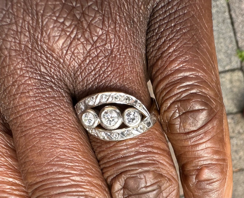 A 14ct white gold ring featuring a navette-shaped face set with three central diamonds and a curved outer frame of smaller accent diamonds. View IV