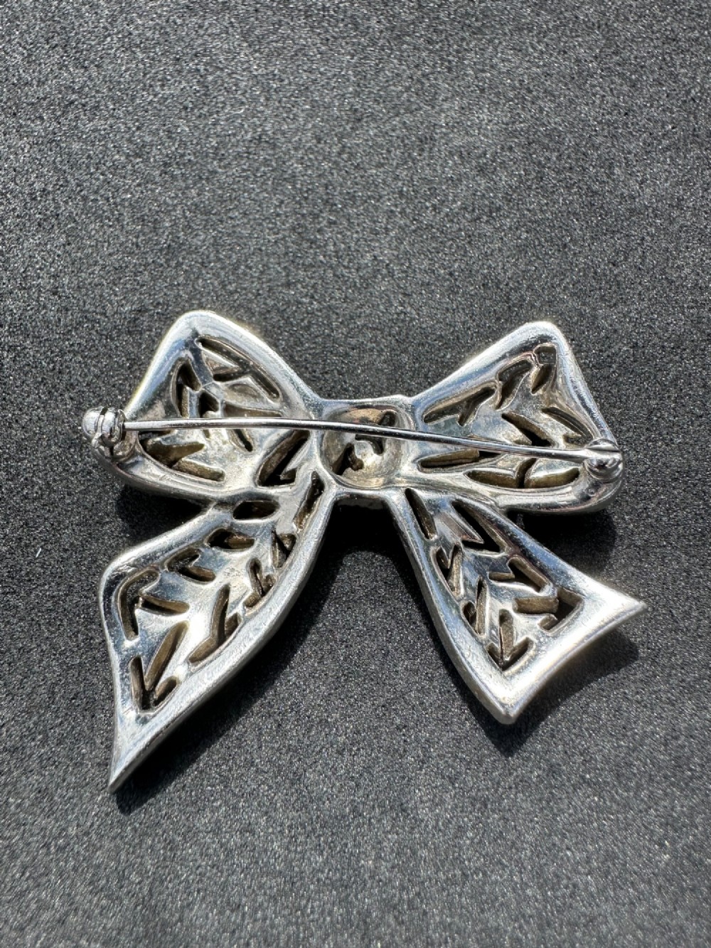 A silver-toned metal bow brooch encrusted with clear paste stones arranged in a geometric openwork pattern. View II