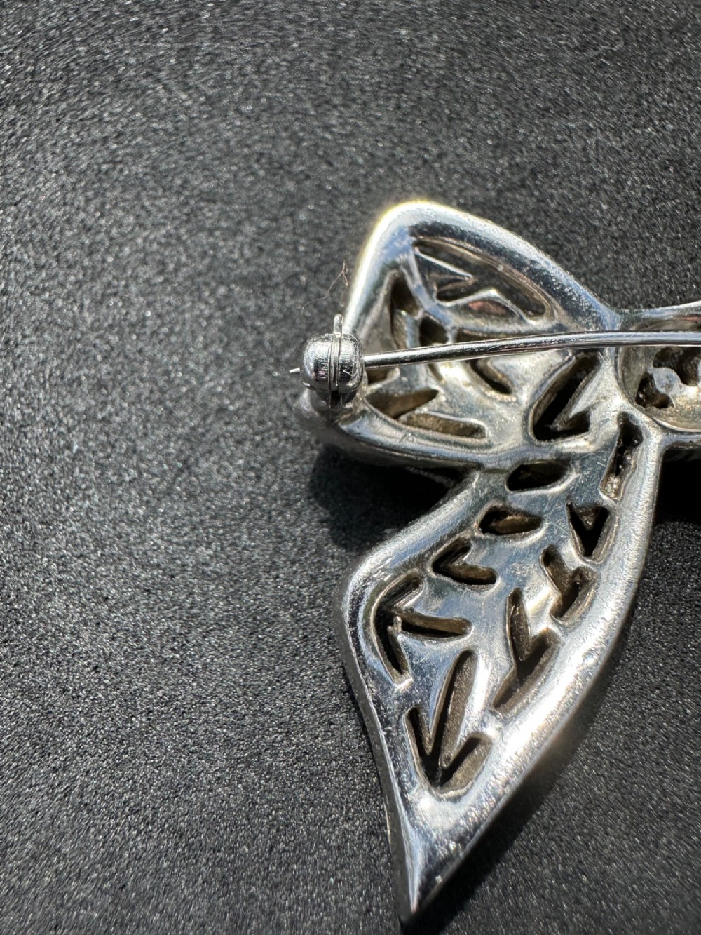A silver-toned metal bow brooch encrusted with clear paste stones arranged in a geometric openwork pattern. View III