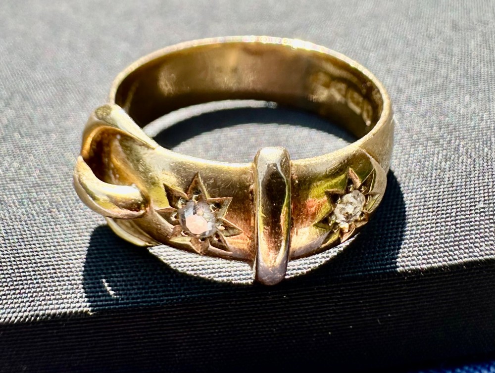 An 18 carat yellow gold band styled as a buckle motif with two star-set diamonds embedded on the surface. View IV