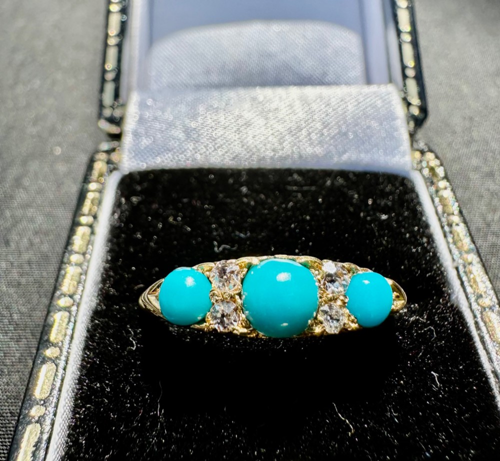 An antique 18ct yellow gold ring set with three turquoise cabochons and four small diamonds.