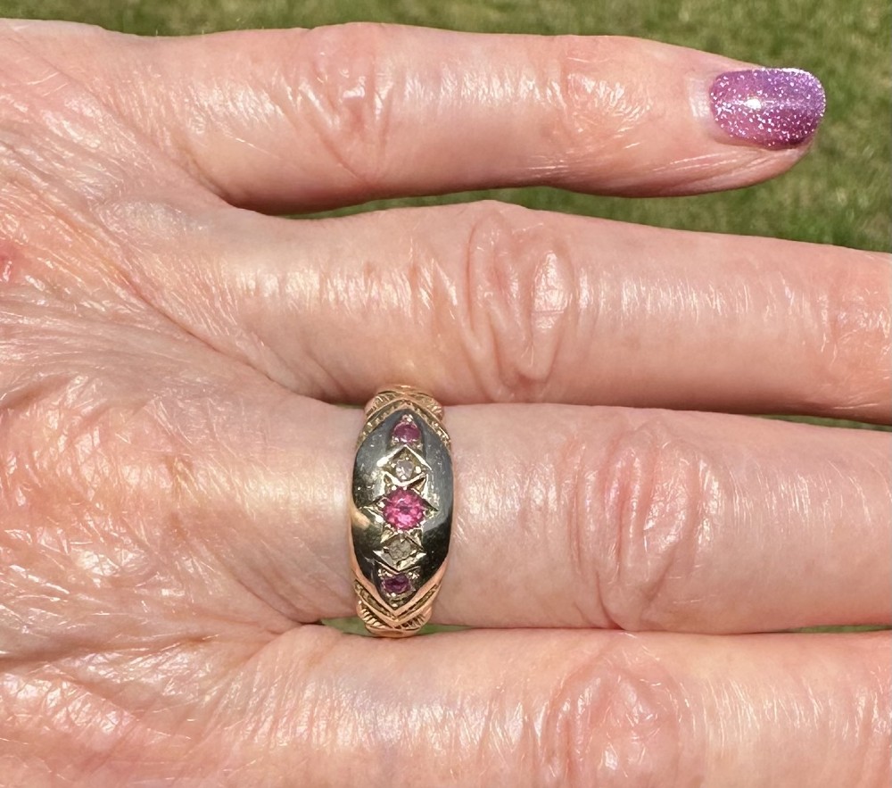 An antique 9ct gold gypsy ring featuring five alternating rubies and diamonds set into star-engraved flush mounts along a carved band. View II