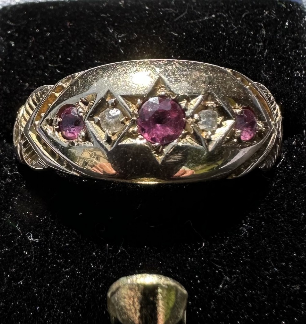 An antique 9ct gold gypsy ring featuring five alternating rubies and diamonds set into star-engraved flush mounts along a carved band. View III