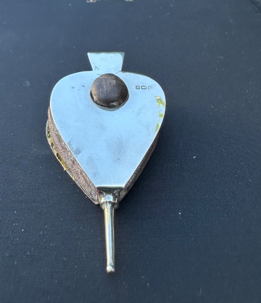 An Edwardian sterling silver pin cushion shaped like fireplace bellows, featuring a central fabric cushion and official British hallmarks.