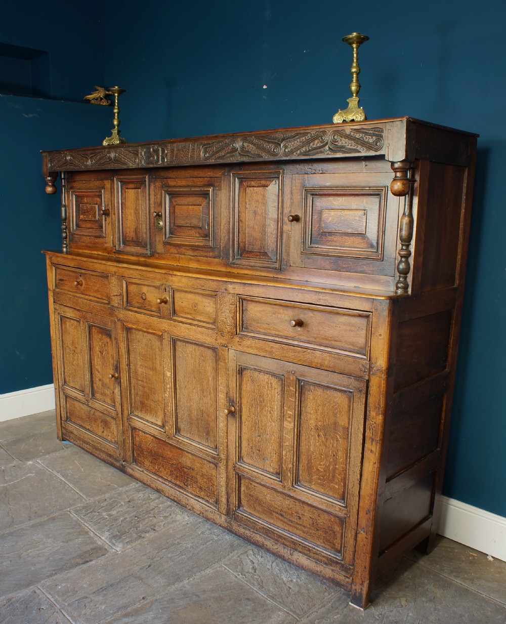 A large 18th-century carved oak court cupboard with recessed upper doors, carved top frieze with initials, and three lower cupboard doors. View II