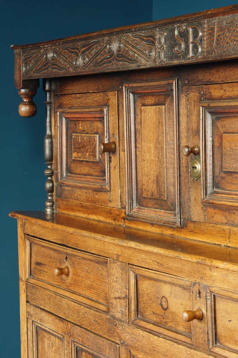 A large 18th-century carved oak court cupboard with recessed upper doors, carved top frieze with initials, and three lower cupboard doors. View VIII