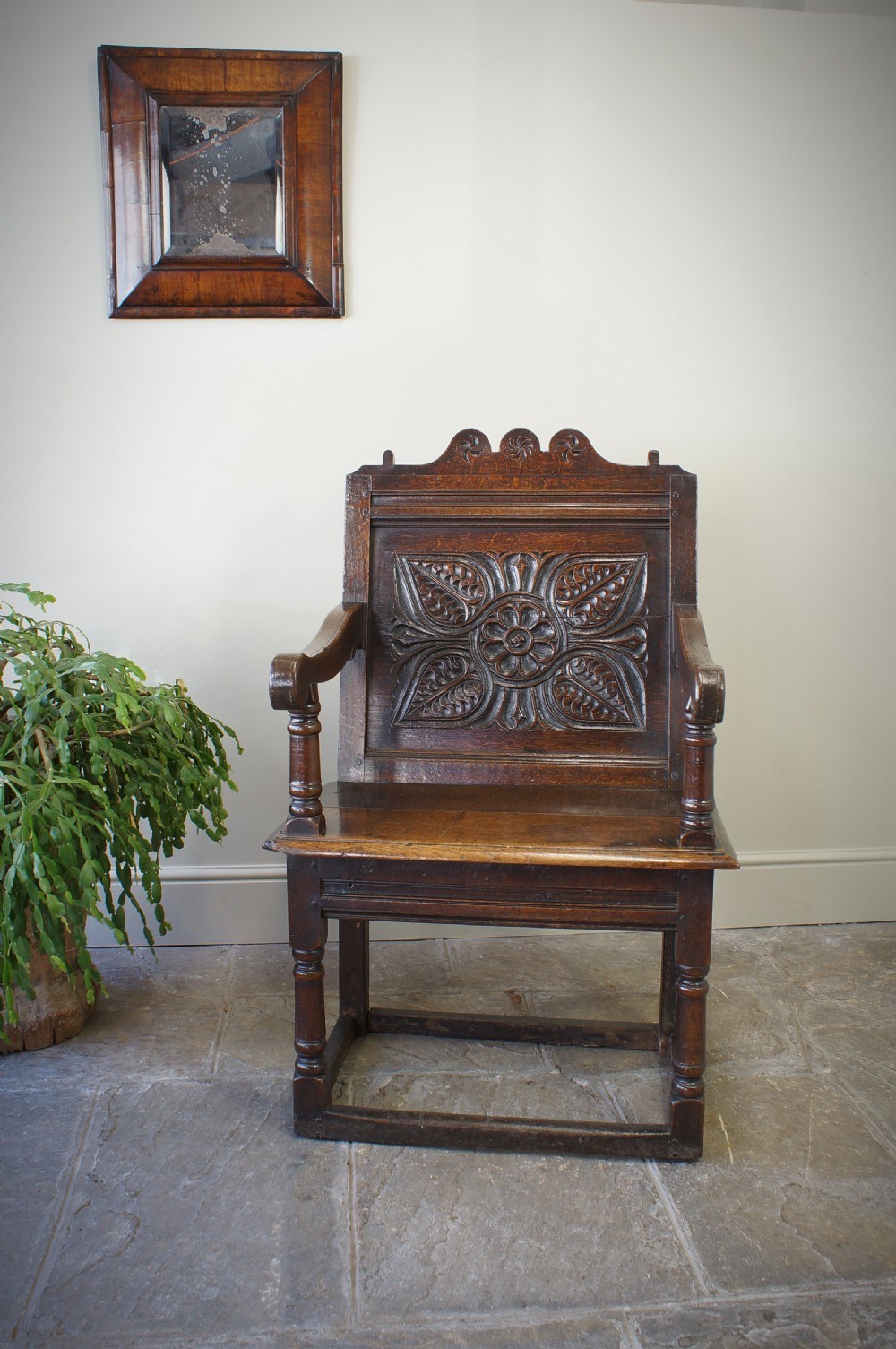 A 17th-century dark oak wainscot armchair with a deeply carved back panel, turned front legs, and sturdy box stretchers. View II
