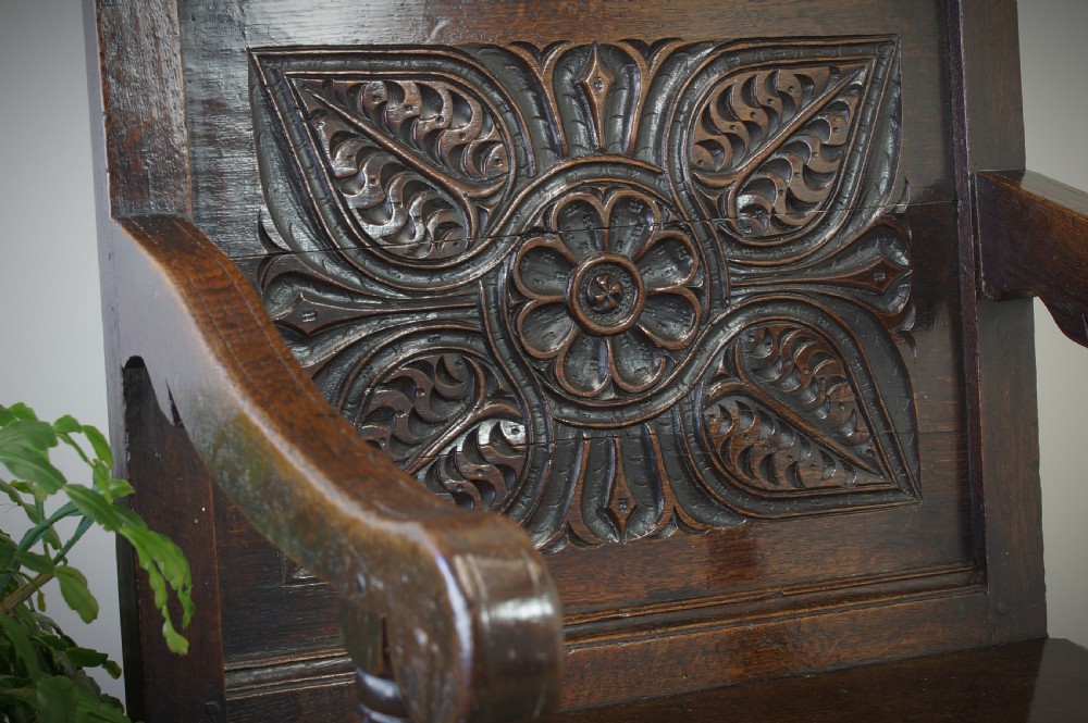 A 17th-century dark oak wainscot armchair with a deeply carved back panel, turned front legs, and sturdy box stretchers. View III