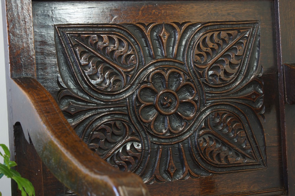 A 17th-century dark oak wainscot armchair with a deeply carved back panel, turned front legs, and sturdy box stretchers. View IV