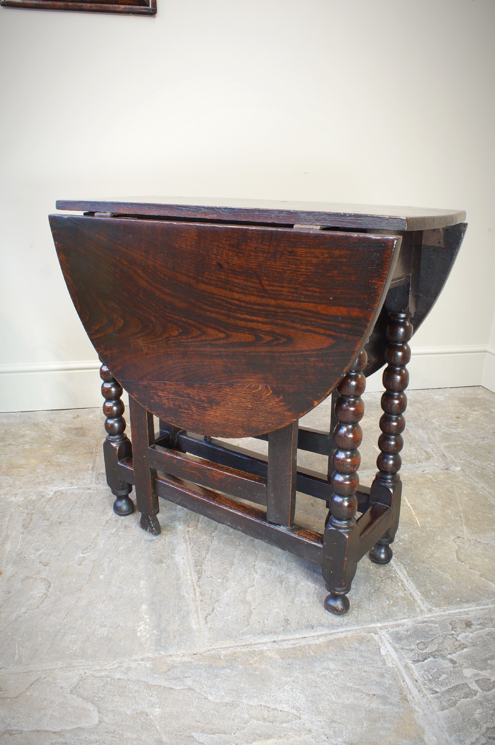 A small 17th-century dark oak gateleg table featuring bobbin-turned legs, drop-leaf top, and lower stretchers. View III