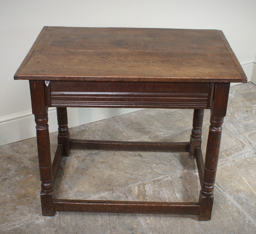 A seventeenth-century dark oak side table featuring a rectangular plank top, moulded apron, turned legs, and perimeter stretchers. View II