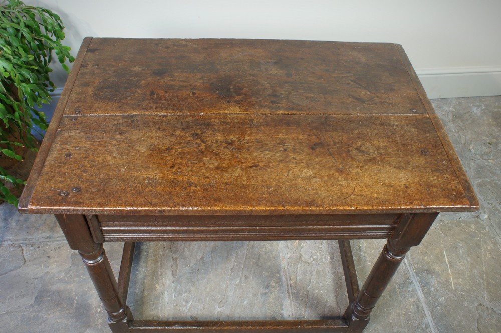 A seventeenth-century dark oak side table featuring a rectangular plank top, moulded apron, turned legs, and perimeter stretchers. View III