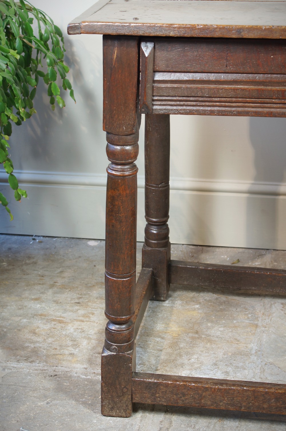 A seventeenth-century dark oak side table featuring a rectangular plank top, moulded apron, turned legs, and perimeter stretchers. View VI