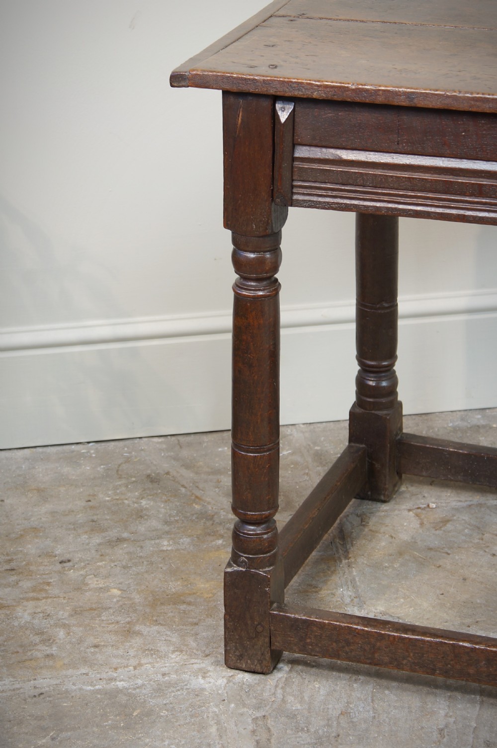 A seventeenth-century dark oak side table featuring a rectangular plank top, moulded apron, turned legs, and perimeter stretchers. View XII