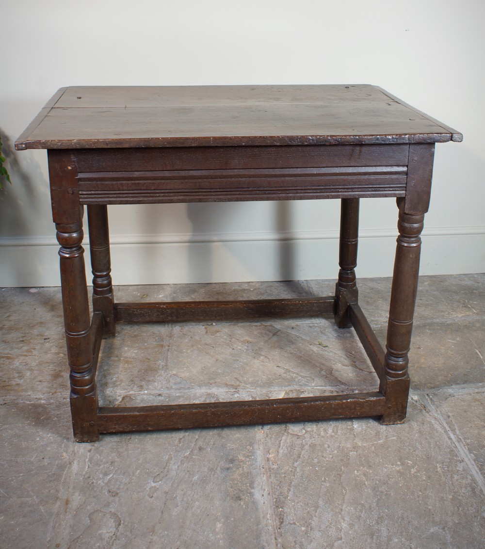 A seventeenth-century dark oak side table featuring a rectangular plank top, moulded apron, turned legs, and perimeter stretchers. View XVI