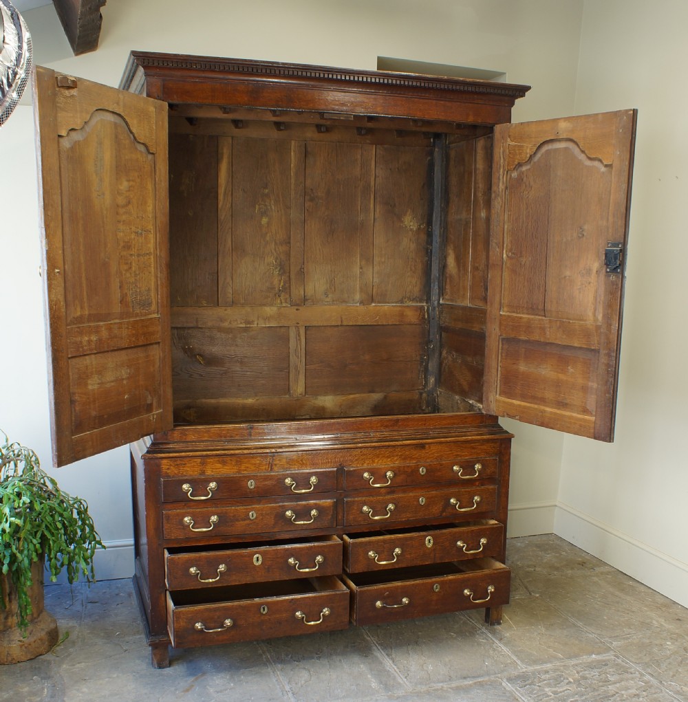 An 18th-century Georgian Welsh oak linen press cupboard featuring two arched panel doors over a base section with four rows of brass-handled drawers. View II
