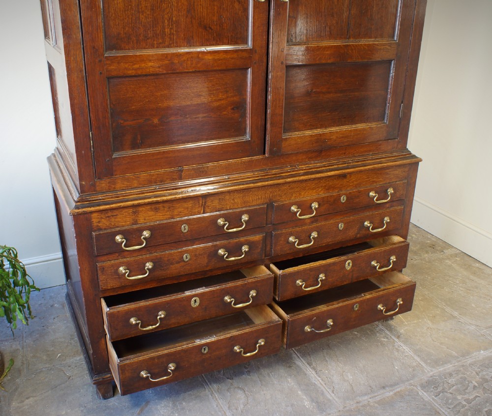 An 18th-century Georgian Welsh oak linen press cupboard featuring two arched panel doors over a base section with four rows of brass-handled drawers. View V