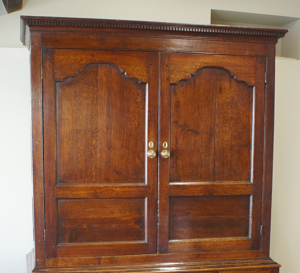 An 18th-century Georgian Welsh oak linen press cupboard featuring two arched panel doors over a base section with four rows of brass-handled drawers. View VI