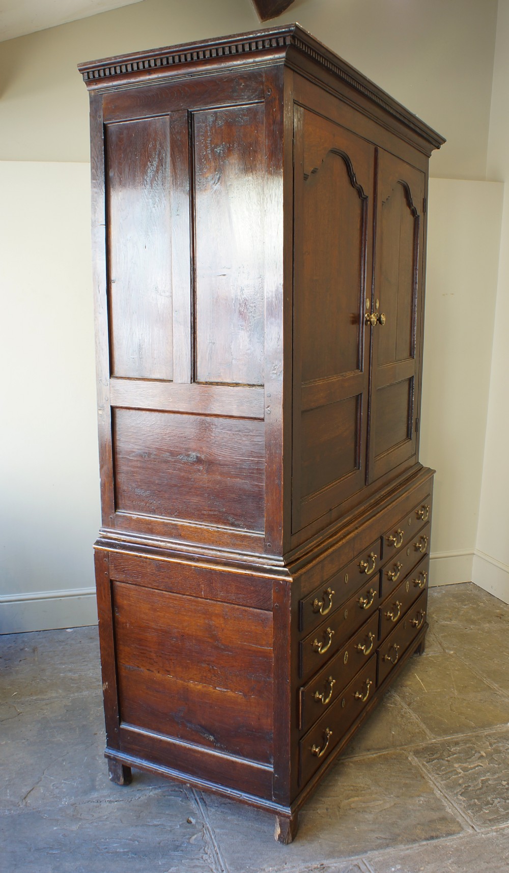 An 18th-century Georgian Welsh oak linen press cupboard featuring two arched panel doors over a base section with four rows of brass-handled drawers. View VIII