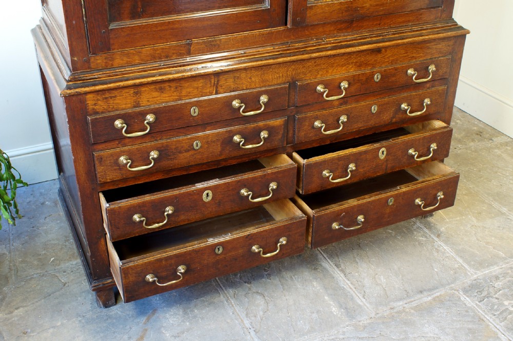 An 18th-century Georgian Welsh oak linen press cupboard featuring two arched panel doors over a base section with four rows of brass-handled drawers. View IX