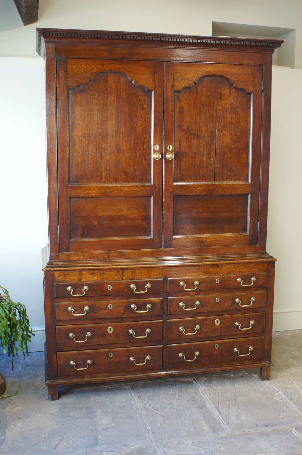 An 18th-century Georgian Welsh oak linen press cupboard featuring two arched panel doors over a base section with four rows of brass-handled drawers. View XII