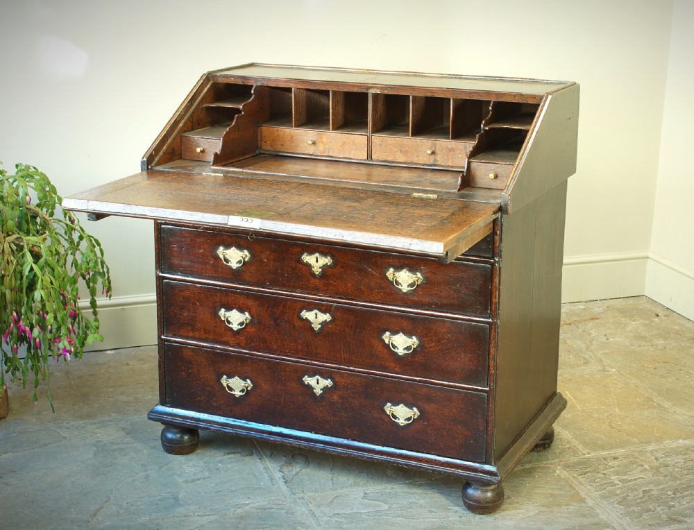 A William and Mary dark oak slant-front bureau featuring geometric parquetry on the lid, three long drawers with brass drop handles, and bun feet. View III