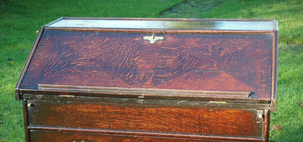 A William and Mary dark oak slant-front bureau featuring geometric parquetry on the lid, three long drawers with brass drop handles, and bun feet. View VIII